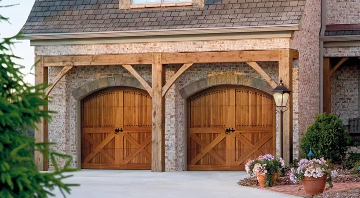 Two woodgrain carriage-style garage doors on a brick home.