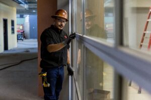 Worker installing glass window panel.