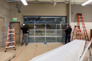 Two workers installing a glass door